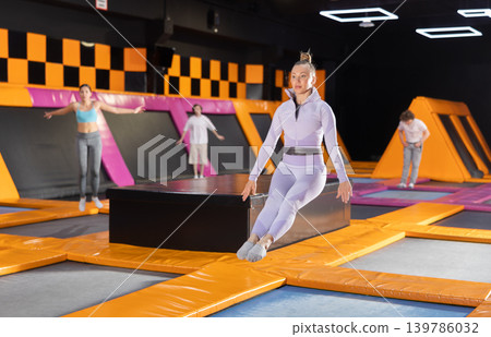 Adult woman trains jumping in trampoline center Adult woman trains jumping in trampoline center 139786032