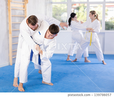 Adult man and young guy training judo techniques Adult man and young guy training judo techniques 139786057