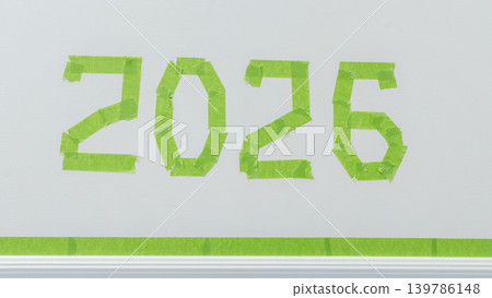 Green painter's tape arranged to form the numbers 2026 on a white wall, showcasing a creative home improvement project Green painter's tape arranged to form the numbers 2026 on a white wall, showcasing a creative home improvement project 139786148