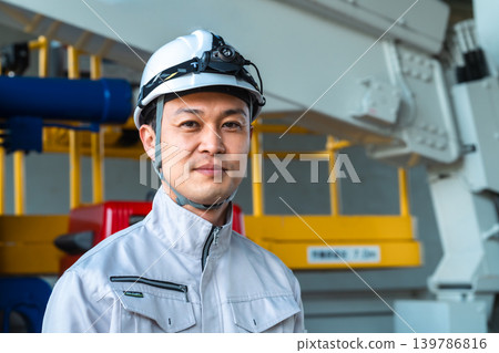 一名身穿工作服、開車燈的男子站在一輛工程車前微笑。 一名身穿工作服、開車燈的男子站在一輛工程車前微笑。 139786816