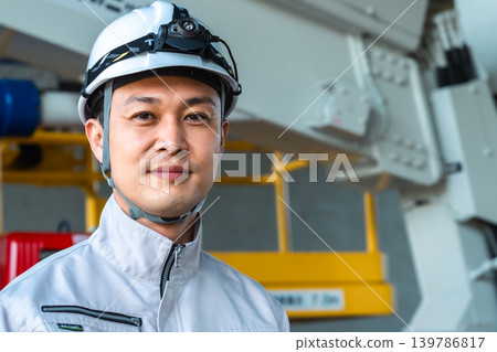 一名身穿工作服、開車燈的男子站在一輛工程車前微笑。 一名身穿工作服、開車燈的男子站在一輛工程車前微笑。 139786817