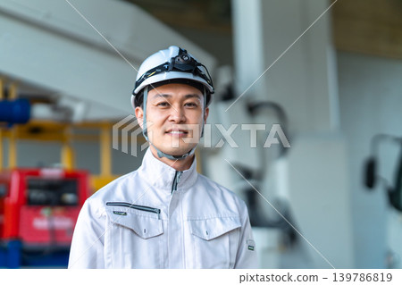 一名身穿工作服、開車燈的男子站在一輛工程車前微笑。 一名身穿工作服、開車燈的男子站在一輛工程車前微笑。 139786819