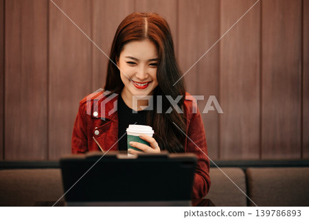 Smiling Asian Businesswoman Working Remotely with Smartphone and Tablet in Cafe Smiling Asian Businesswoman Working Remotely with Smartphone and Tablet in Cafe 139786893