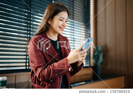 Asian female freelancer using laptop and smartphone in a cafe, representing modern digital lifestyle, remote work 139786928