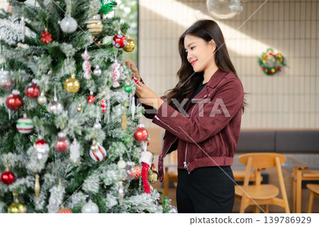 Asian Woman Decorating Christmas Tree at Home | Festive Holiday Lifestyle and Seasonal Celebration 139786929