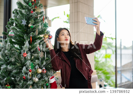 Asian Woman Decorating Christmas Tree at Home | Festive Holiday Lifestyle and Seasonal Celebration 139786932