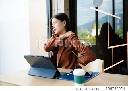 Overworked young Asian businesswoman office worker suffering from neck pain after had a long day at her office desk. office syndrome 139786954