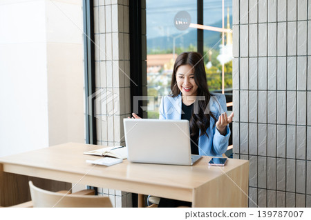 Asian businesswoman using smartphone and laptop in modern office. Professional female entrepreneur multitasking 139787007