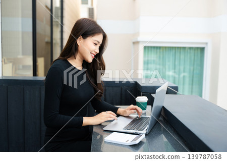 Asian woman using laptop and tablet while sitting at her working place. Asian woman using laptop and tablet while sitting at her working place. 139787058