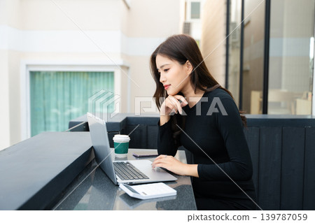 Asian woman using laptop and tablet while sitting at her working place. Asian woman using laptop and tablet while sitting at her working place. 139787059