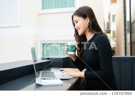 Asian woman using laptop and tablet while sitting at her working place. Asian woman using laptop and tablet while sitting at her working place. 139787060