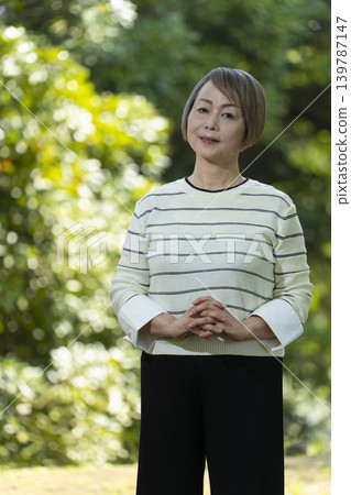 幾位老年婦女在綠樹環繞的公園散步。 139787147