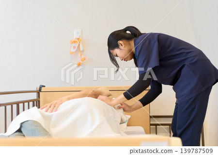 Foreign caregivers performing sponge baths on elderly patients 139787509