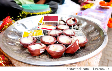 Clay diyas with wax candles arranged on metal plate with matchbo 139788203