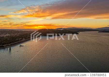 Aerial view of Glenbawn Dam at sunset in NSW Australia. Drone photograph captures calm dam waters, surrounding hills and colourful evening sky reflections from above. Scenic Australian inland 139788451