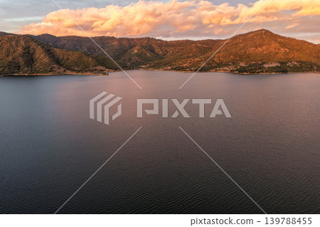 Aerial view of Glenbawn Dam at sunset in NSW Australia. Drone photograph captures calm dam waters, surrounding hills and colourful evening sky reflections from above. Scenic Australian inland 139788455