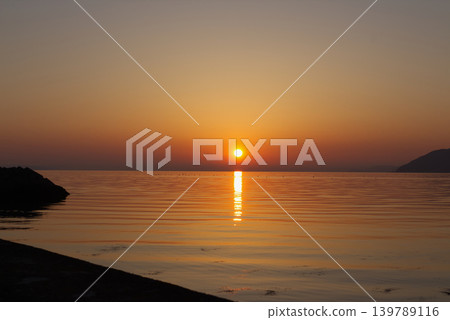 A beautiful sunrise and a path of light shimmering on the sea, as seen from Aioi Fishing Port in Higashikagawa City, Kagawa Prefecture. A beautiful sunrise and a path of light shimmering on the sea, as seen from Aioi Fishing Port in Higashikagawa City, Kagawa Prefecture. 139789116