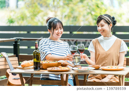 年輕女性在露臺上享受美食、燒烤、家庭聚會以及與朋友一起體驗豪華露營。 年輕女性在露臺上享受美食、燒烤、家庭聚會以及與朋友一起體驗豪華露營。 139789339