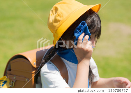 小學生在上下學的路上用毛巾擦汗。 小學生在上下學的路上用毛巾擦汗。 139789737