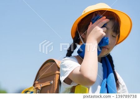 小學生在上下學的路上用毛巾擦汗。 139789738