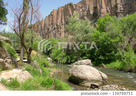 Scenic Ihlara Valley Canyon in Cappadocia. A breathtaking view of the green Ihlara Valley gorge in Turkey, featuring steep volcanic cliffs, ancient cave dwellings, and lush forests. Scenic Ihlara Valley Canyon in Cappadocia. A breathtaking view of the green Ihlara Valley gorge in Turkey, featuring steep volcanic cliffs, ancient cave dwellings, and lush forests. 139789751