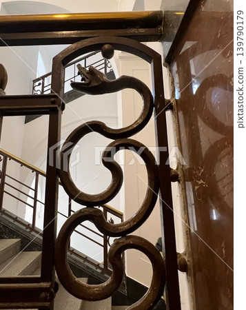 Ornate metal railing featuring a decorative snake design, showcasing intricate curves and Ornate metal railing featuring a decorative snake design, showcasing intricate curves and 139790179