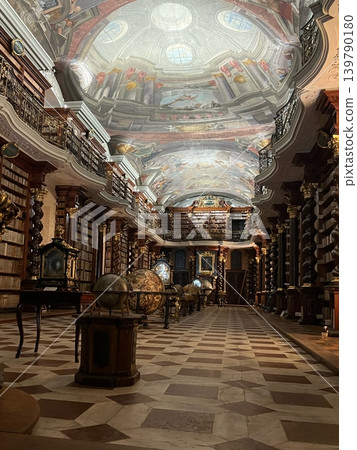 Grand historic library interior featuring ornate ceiling frescoes, wooden bookshelves filled with 139790180