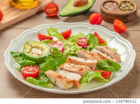 Grilled chicken salad with avocado tomatoes and lettuce on wooden table Grilled chicken salad with avocado tomatoes and lettuce on wooden table 139790312