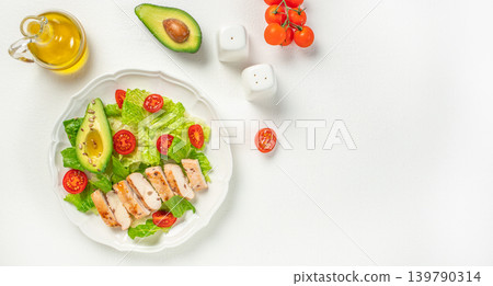 Healthy chicken avocado salad with cherry tomatoes on white background top view Healthy chicken avocado salad with cherry tomatoes on white background top view 139790314