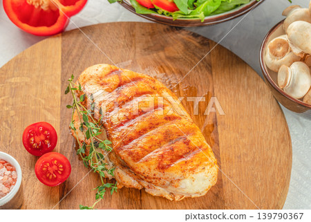Grilled chicken breast with fresh salad and vegetables on wooden serving board Grilled chicken breast with fresh salad and vegetables on wooden serving board 139790367