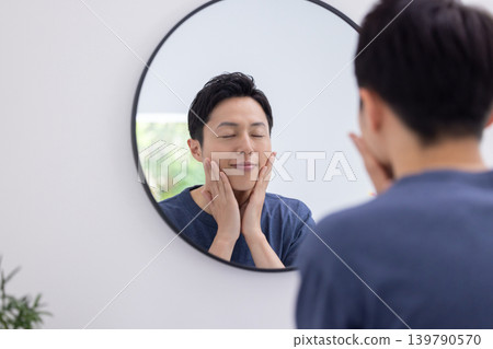 美妝圖片:一位男士正在對著鏡子進行護膚。 美妝圖片:一位男士正在對著鏡子進行護膚。 139790570