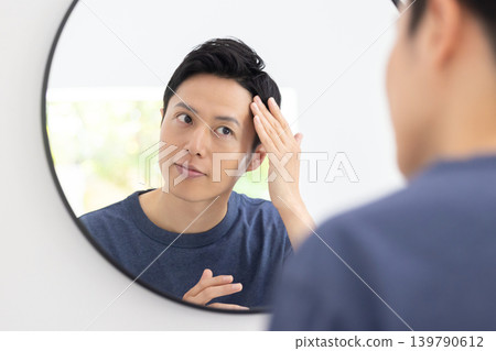 美妝圖片：一位男士正在對著鏡子進行護膚。 139790612