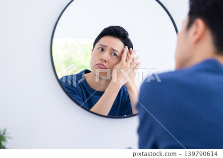 美妝圖片：一位男士正在對著鏡子進行護膚。 139790614