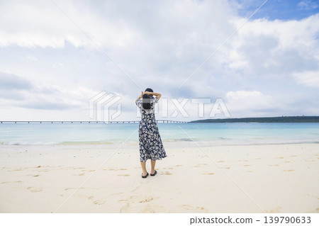 A woman looking at Kurima Bridge from Yonaha Maehama Beach. 139790633