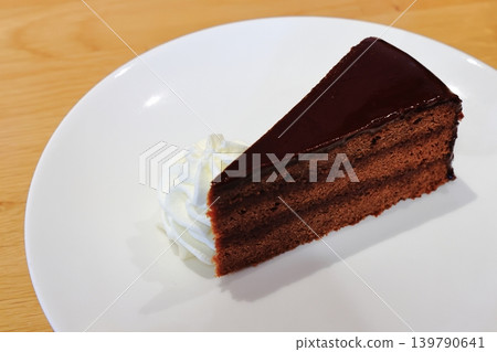 Sachertorte, a famous chocolate cake from Vienna, Austria, served on a white plate with whipped cream. Sachertorte, a famous chocolate cake from Vienna, Austria, served on a white plate with whipped cream. 139790641