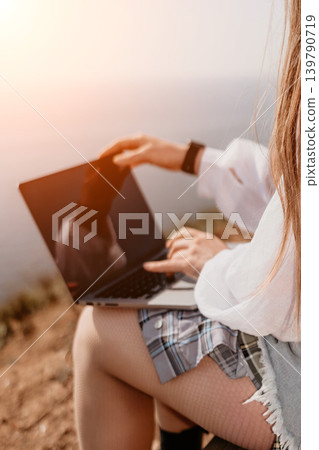 Woman laptop work using portable computer on a cliff overlooking the sea at sunset for remote lifestyle and digital nomad concept Woman laptop work using portable computer on a cliff overlooking the sea at sunset for remote lifestyle and digital nomad concept 139790719