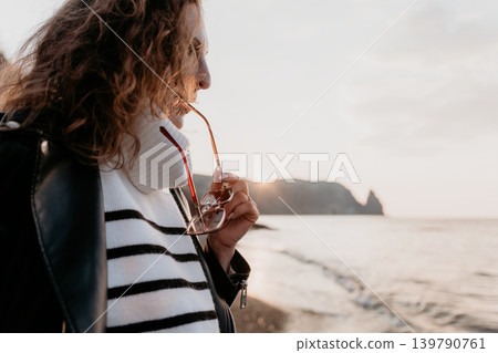 Woman Ocean Sunset curly haired lady wearing leather jacket looking at the coast during golden hour with copy space Woman Ocean Sunset curly haired lady wearing leather jacket looking at the coast during golden hour with copy space 139790761