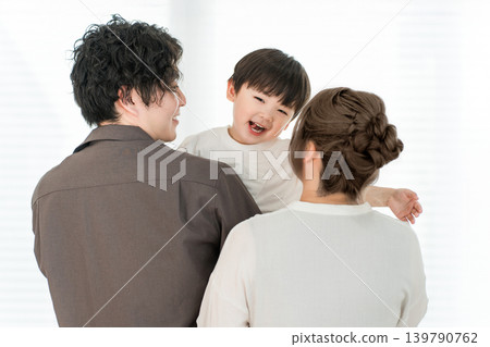 A smiling boy being held by his parents at home (family, parent and child) A smiling boy being held by his parents at home (family, parent and child) 139790762