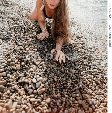 Pebbles woman beach young woman with long hair playing with smooth stones on a rocky shore during summer vacation under bright sun Pebbles woman beach young woman with long hair playing with smooth stones on a rocky shore during summer vacation under bright sun 139790780