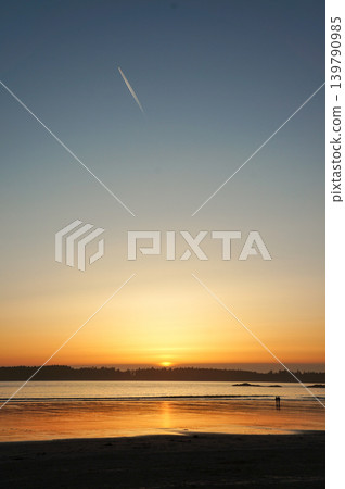 The sunset sinking into the quiet seashore and the trail of an airplane The sunset sinking into the quiet seashore and the trail of an airplane 139790985