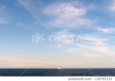 一艘小船漂浮在平靜的海面上，天空飄著柔和的雲朵。 139791125