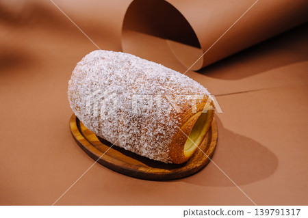 Sweet pastry on a wooden plate against brown background in a simple setting Sweet pastry on a wooden plate against brown background in a simple setting 139791317