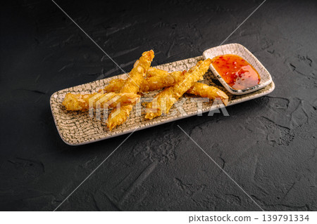 Crispy shrimp with dipping sauce served on a plate with a textured surface Crispy shrimp with dipping sauce served on a plate with a textured surface 139791334