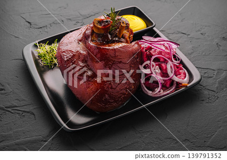 Delicious pork knuckle dish served with onions and mustard on a black plate Delicious pork knuckle dish served with onions and mustard on a black plate 139791352