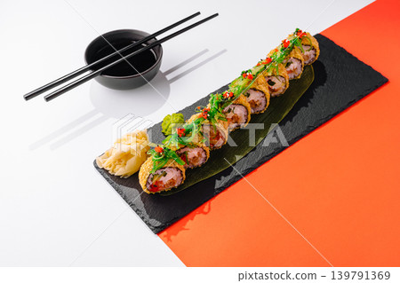 Sushi served on a black plate with chopsticks and dipping sauce on the side Sushi served on a black plate with chopsticks and dipping sauce on the side 139791369