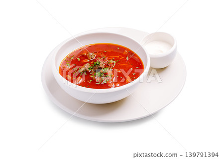 Warm borscht or tomato soup served with a side of cream on a white plate Warm borscht or tomato soup served with a side of cream on a white plate 139791394