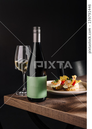 Wine bottle and glass with dish on table in restaurant setting at night Wine bottle and glass with dish on table in restaurant setting at night 139791446