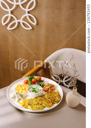 Healthy vegetable pancakes served on a plate on a table in a warm setting Healthy vegetable pancakes served on a plate on a table in a warm setting 139791455