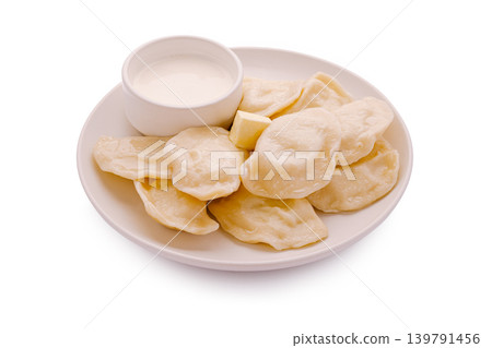 Dumplings served with sour cream on a white plate in a simple setting Dumplings served with sour cream on a white plate in a simple setting 139791456