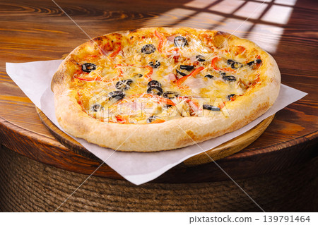 Pizza with cheese, vegetables, and olives placed on a wooden table Pizza with cheese, vegetables, and olives placed on a wooden table 139791464